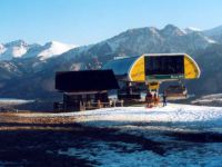 na górze, przy górnej stacji wyciągu, rozświetlone słońcem pasmo ośnieżonych szczytów